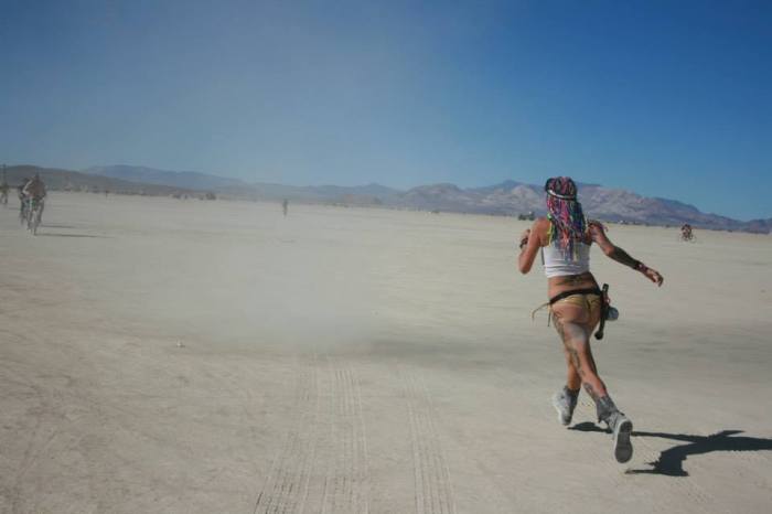 A girl chases a dust devil at burning man