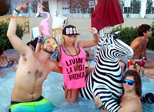 Burning man participants at the after party in a hot tub on an inflatable zebra
