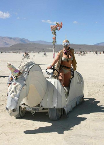 A girl riding a unicorn art car at burning man