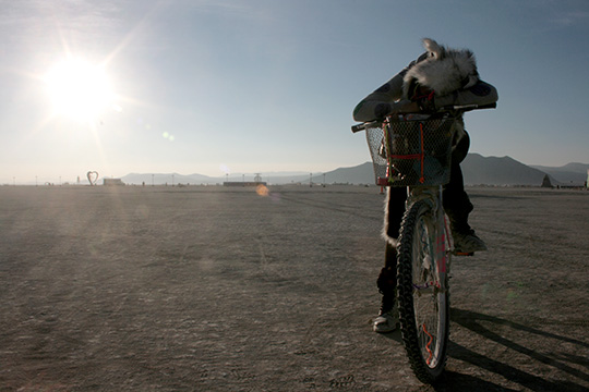 Girl sleeping on bike as sun rises at burning man