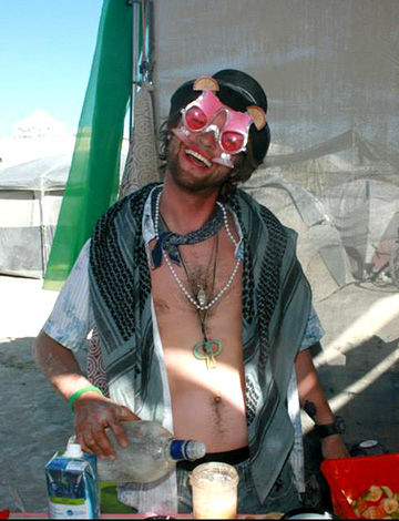 A man wears silly sunglasses and serves drinks at burning man