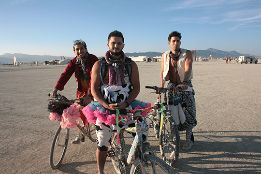 3 men on bikes at burning man in tutu's