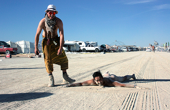 man on dusty ground naked at burning man