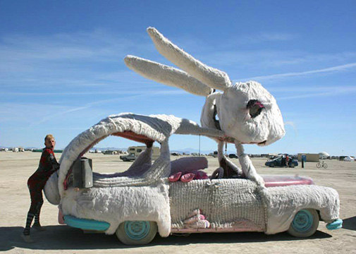 Man standing next to bunny inspired art car at Burning Man