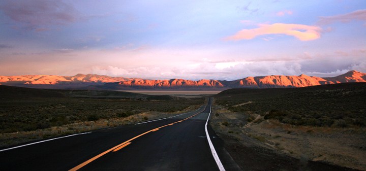 Open road with mountains in distance sunset