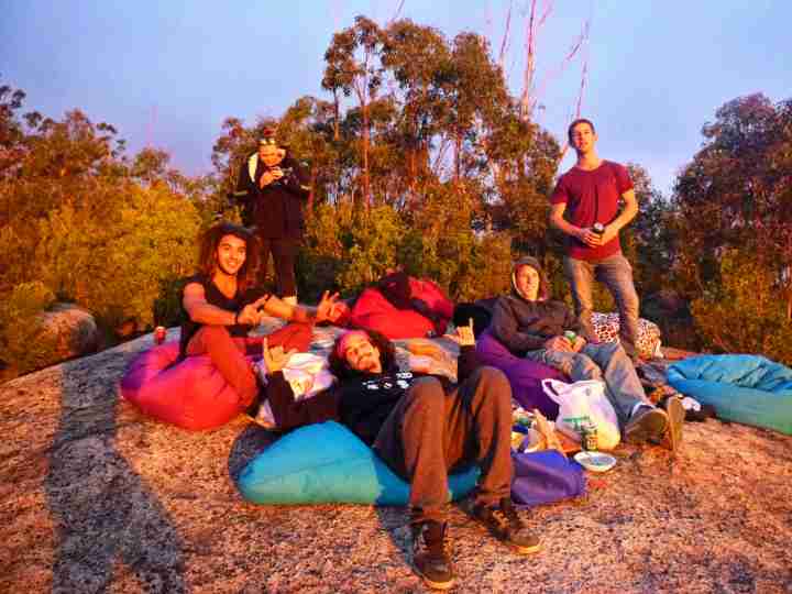 friends sitting on rock at sunset